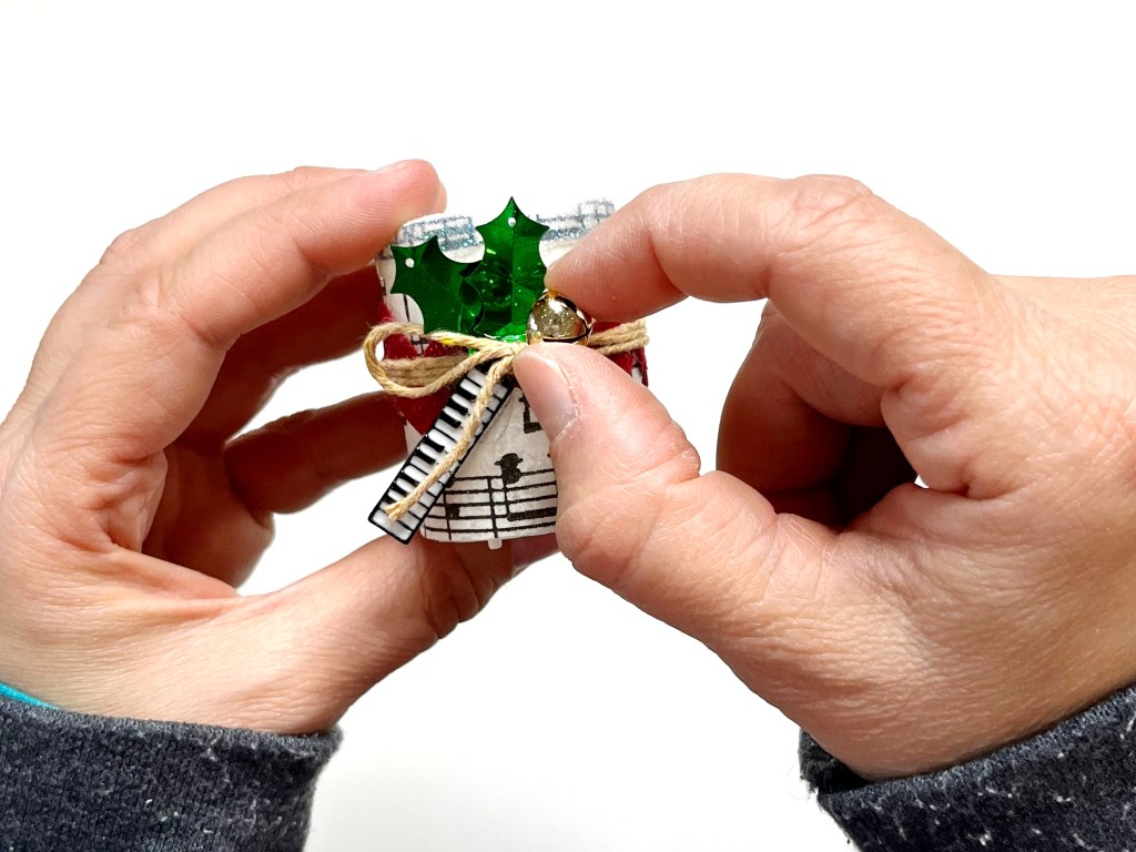 A golden jingle bell is hot glued to the candle and holly leaves as a final embellishment.