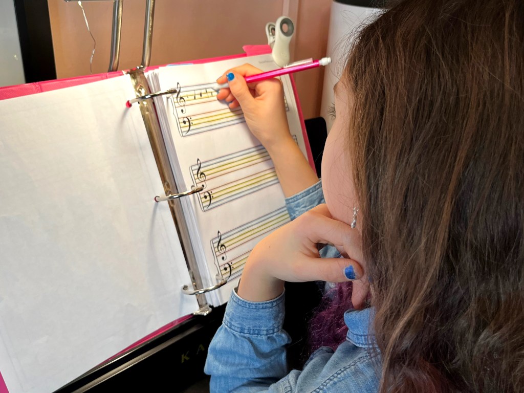Piano student composes an original song on a piece of rainbow manuscript paper.