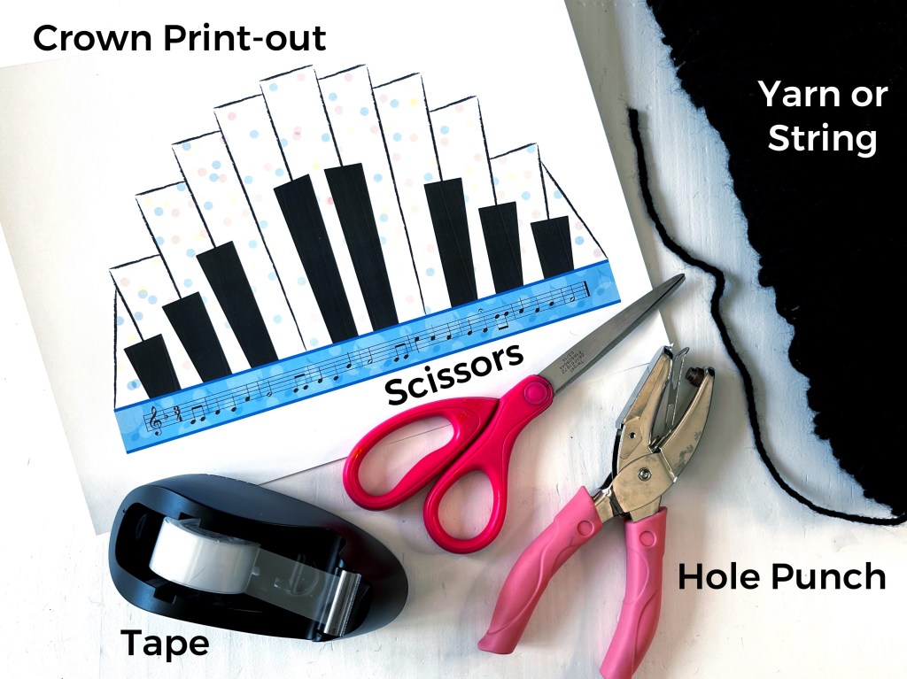 Piano birthday crown printout laying on a white table surrounded by supplies needed to put the crown together: black yarn, transparent tape, a pair of scissors and and holes punch.