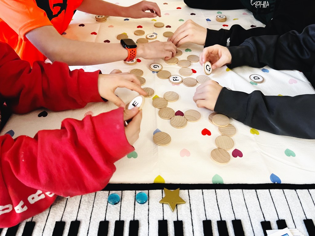 Piano students race to complete their chord by flipping over wooden circles with pitch names on them.