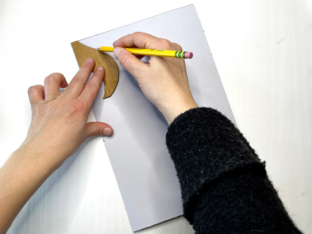 Hands trace an eighth note flag cardboard stencil onto the backing of a sheet of self-adhesive craft foam 