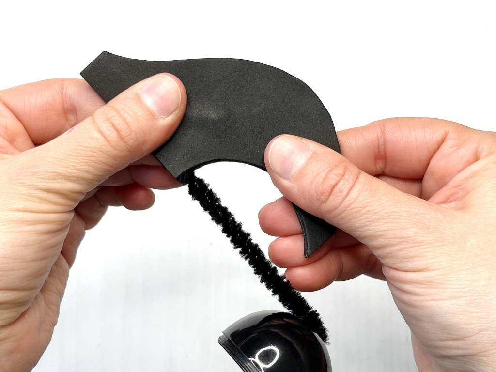 Hands press together two pieces of black self adhesive craft foam