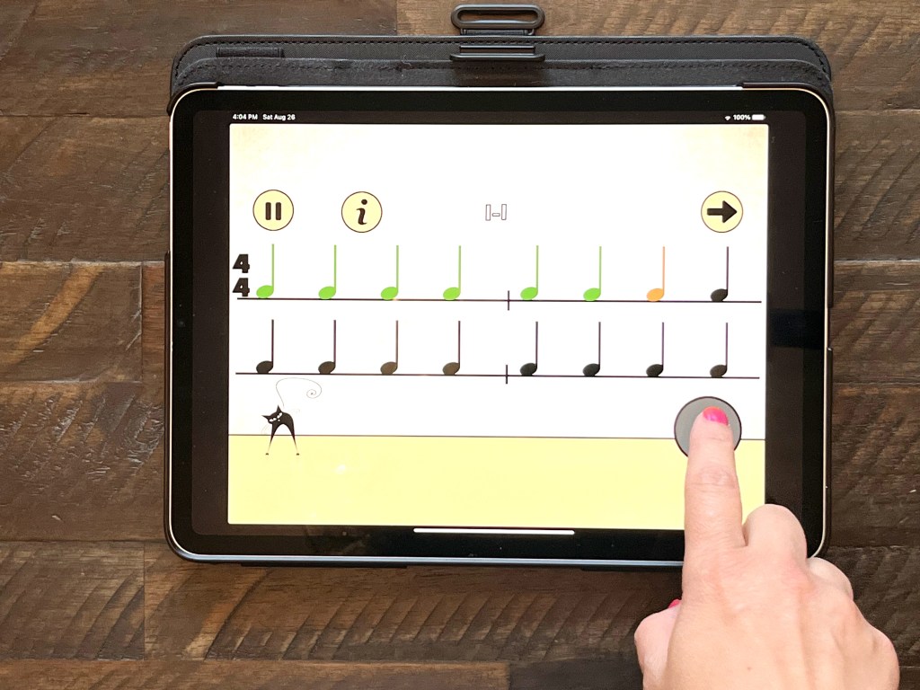 A piano student plays the app Rhythm cat on a tablet sitting on a brown wooden table
