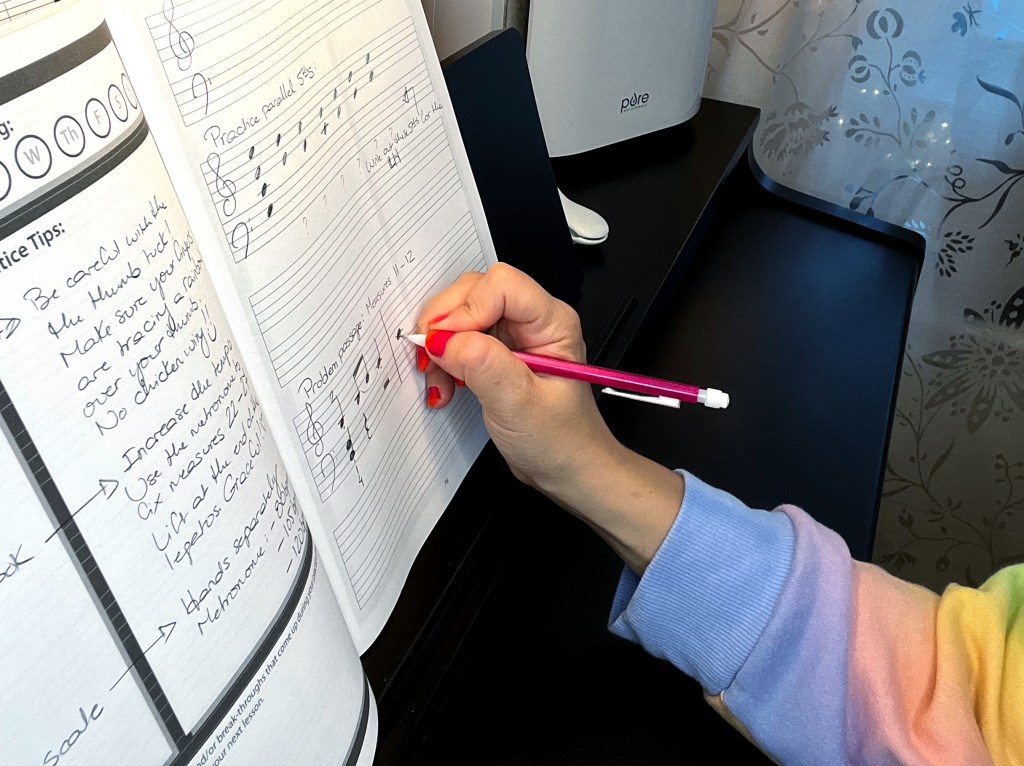 Piano student copies out a problem passage in their practice journal.