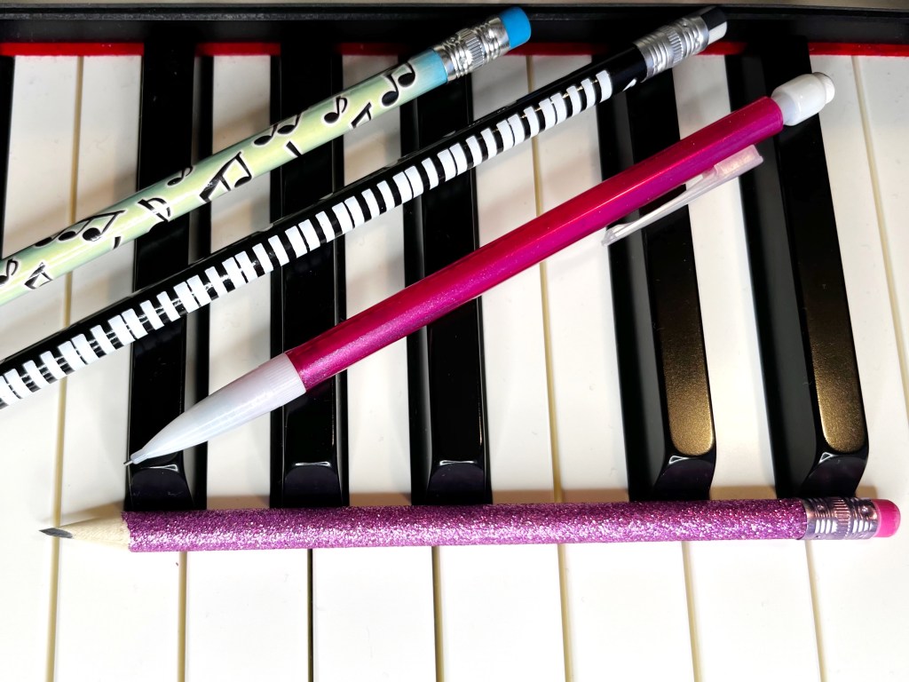 Pencils lay on top of piano keys.