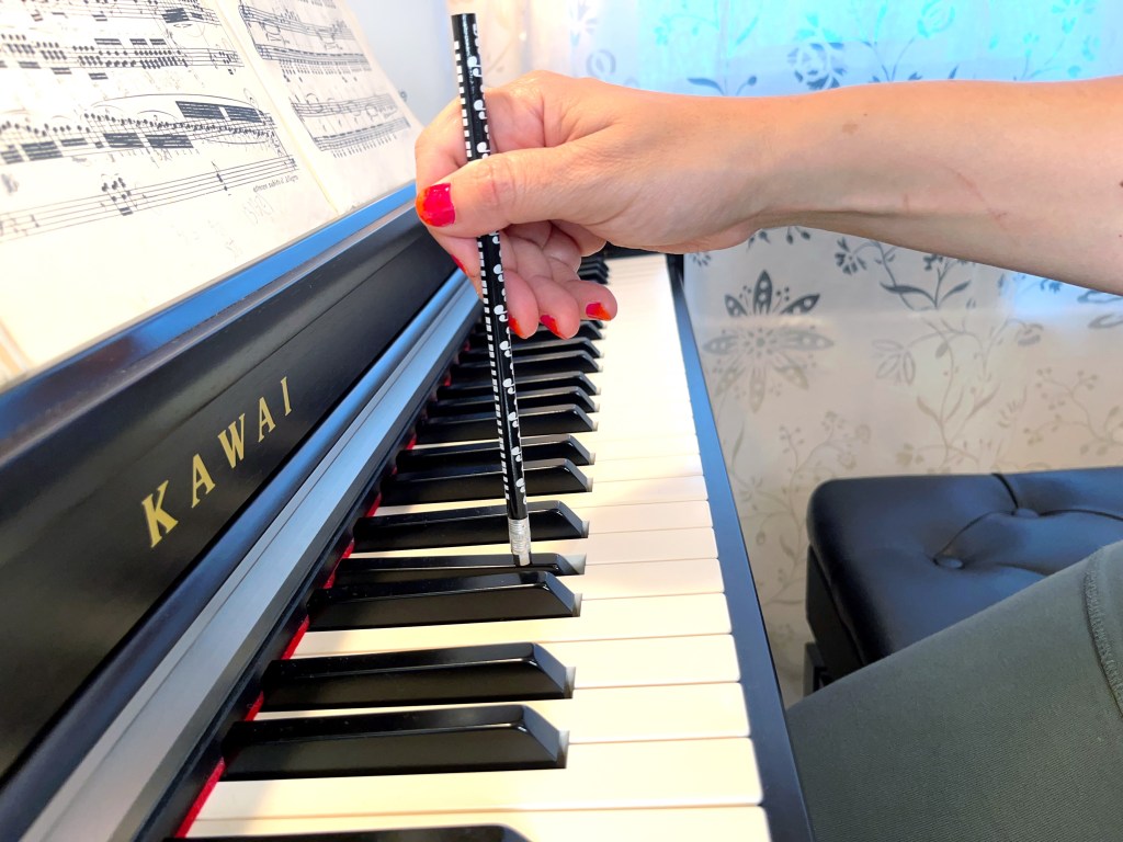 A piano student uses the eraser end of a pencil to play the piano.