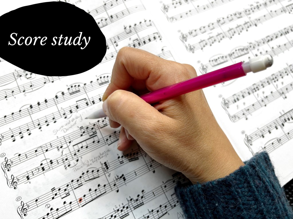A hand holds a pink pencil as a piano students writes important practice notes on a score.