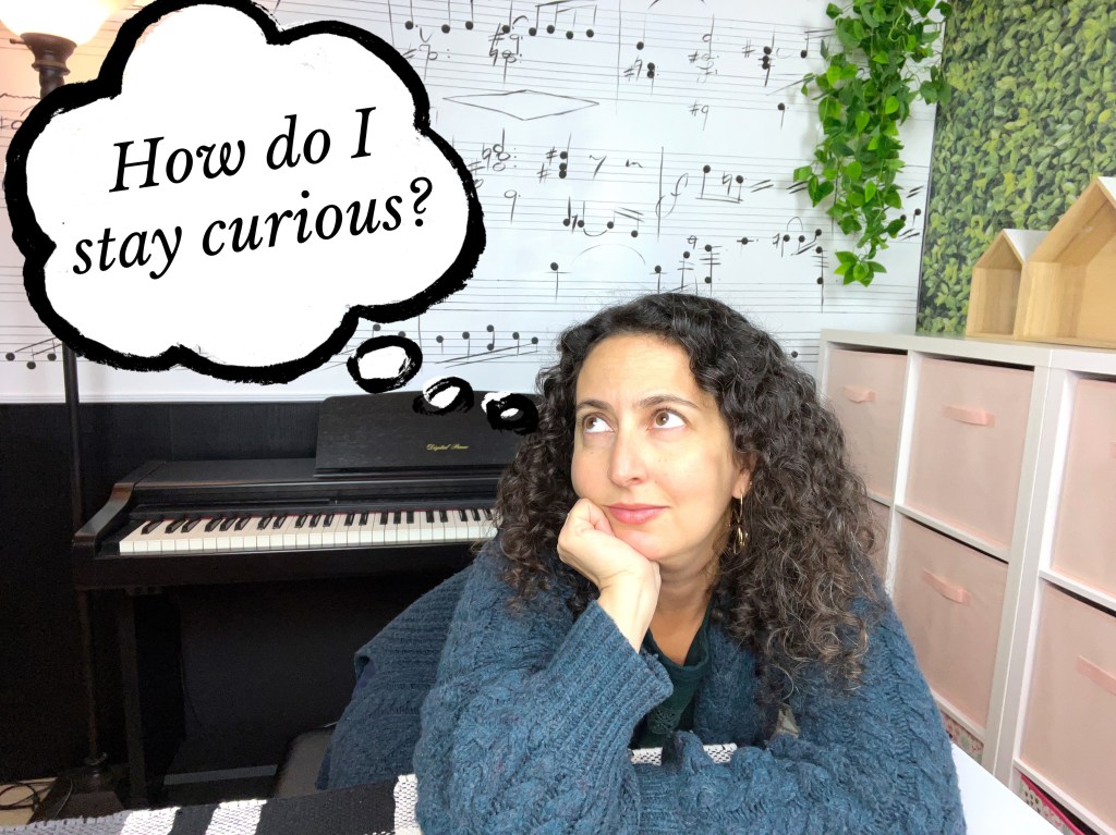 Piano teacher sits at a table in front of a piano with her hand on her chin. A thought bubble is coming out of her head and it reads How do I stay curious?