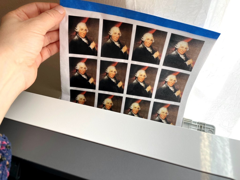 A sheet with mutliple images of the classsical music composer Joseph Haydn exits a printer.