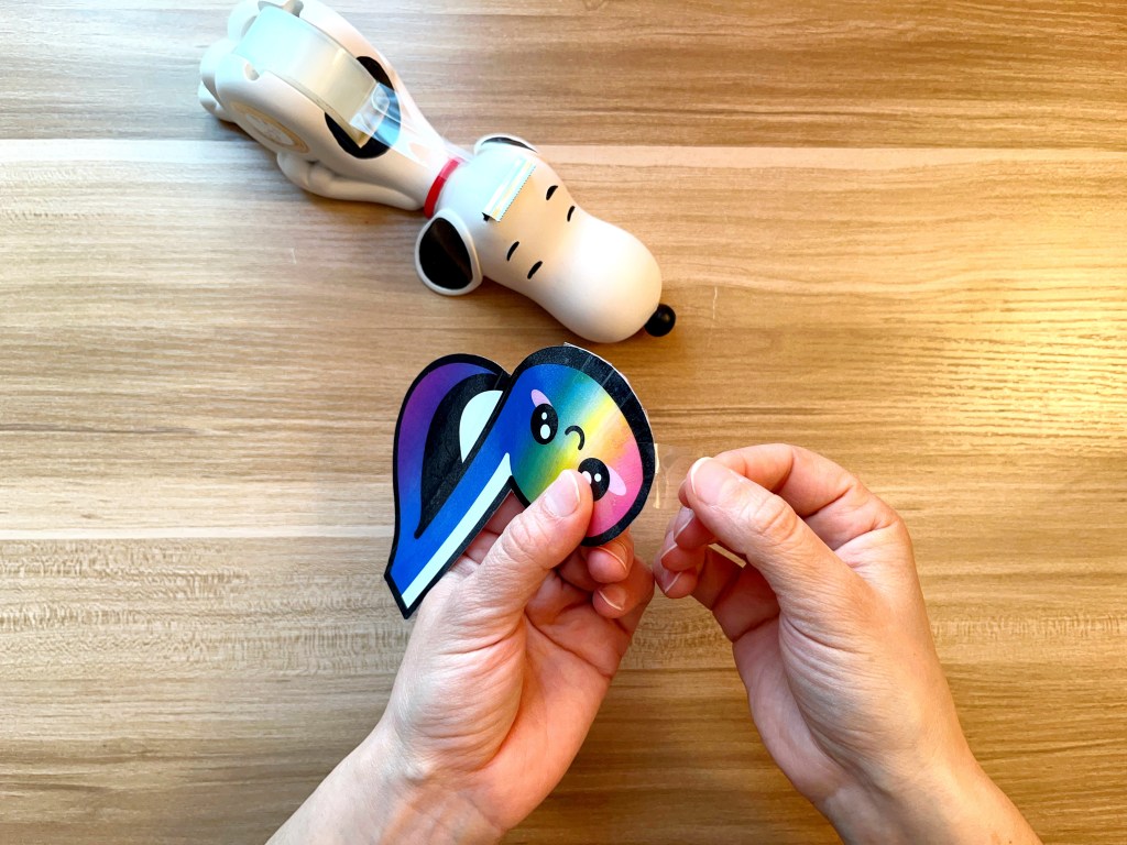 Sealing a rainbow colored paper eighth note squishy with transparent tape
