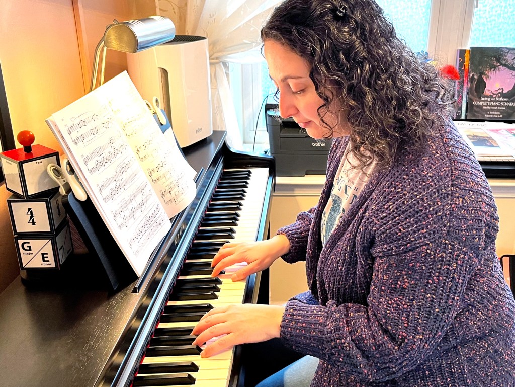Piano student looks down at her hands while playing the piano.