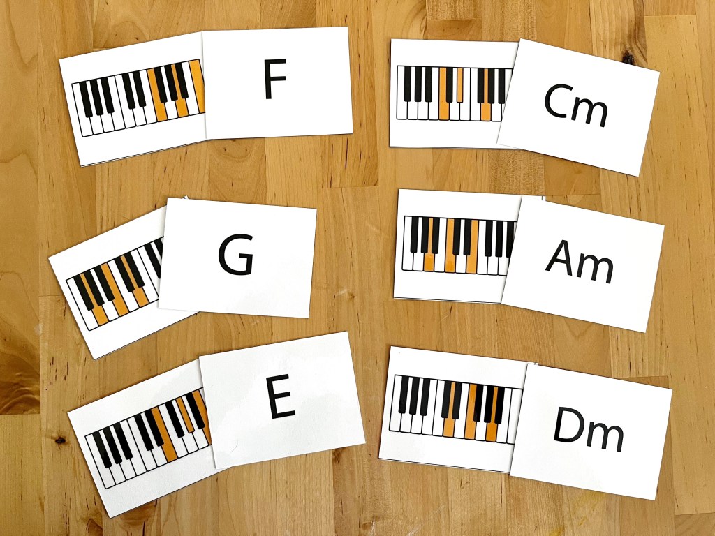 Chord flashcards are paired up on a table. The chord symbol matching the highlighted keys on the keyboard cards.