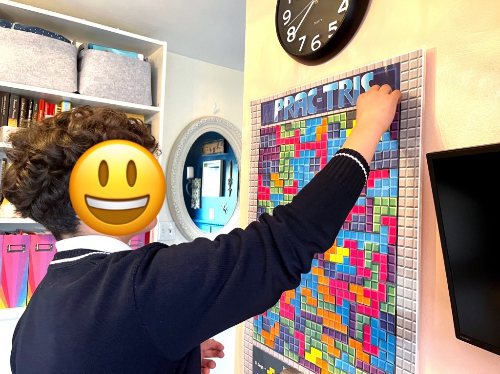 Piano student places a Prac-Tris game block on the Prac-Tris poster.