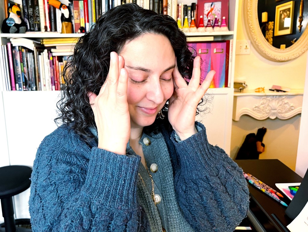 A tired piano student rubs the temples of her head with her fingers.